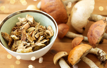 culinary, food and cooking concept - dried mushrooms in bowl on wooden background