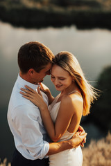 Beautiful young couple embracing and smiling while spending time in nature. A beautiful couple is hugging at romantic date on the beach.