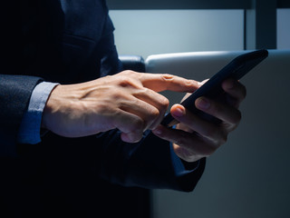 Smartphone in hands. Close-up finger of businessman touching and scroll on mobile phone screen.
