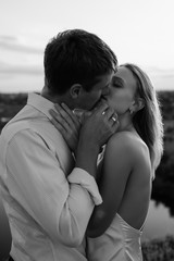 Black and white portrait of young romantic couple. They is kissing and enjoying the company of each other. Sensual couple getting closer to feel each others lips.