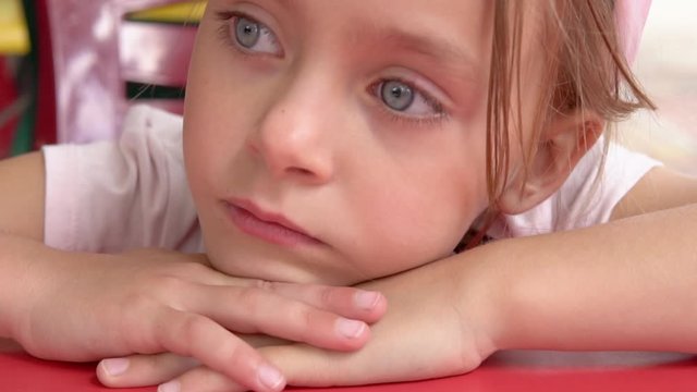 little pensive girl at a red table