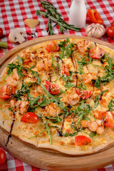 Pizza with seafood, mozzarella, mussels, octopus, squid, salmon, shrimp, cheeseand, fresh rucola and tomatoes sauce in italian restaurant background, top view. Mediterranean food.