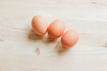 Three chicken eggs on a wooden cutting board