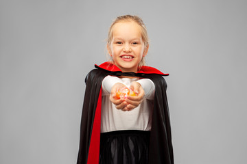 halloween, holiday and childhood concept - happy smiling girl in black dracula cape or costume with...