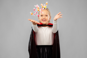 halloween, holiday and childhood concept - happy smiling girl in black dracula cape or costume with...