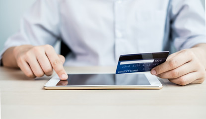 The businesswoman's hand is holding a credit card and using a laptop for online shopping and internet payment in the office
