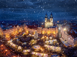 Fototapeta na wymiar Der traditionelle Weihnachtsmarkt auf dem Platz in der Altstadt von Prag, Tschechien, mit festlicher Beleuchtung zur Adventszeit und Schneefall