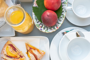 Petit déjeuner pour deux servis sur une nappe blanche avec café, thé, jus d'orange, fruits et gâteaux.	