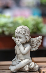 Fototapeta na wymiar Winged little angel sculpture among flowers