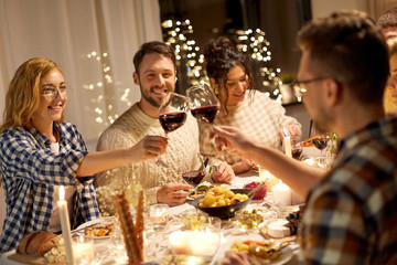 holidays, celebration and people concept - happy friends having christmas dinner party and drinking non-alcoholic red wine at home