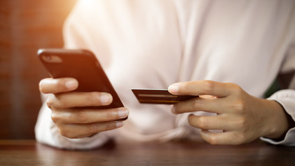 Close up and selective focus of a teenage woman hands holding credit card and smart phone make online payment for shopping. Stock photo.