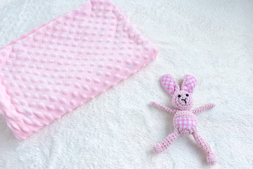 Pink blanket for baby girl and toy on a white fur carpet. Newborn Baby Concept. Baby Girl Clothes...