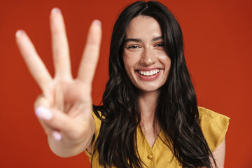 Image of caucasian smiling woman showing three finger at camera
