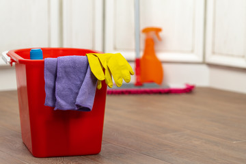 Various household cleaning detergents and bottles in a plastic bucket on the floor