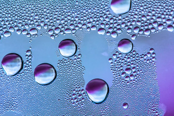 Blue and purple water drops on the glass, abstract background, large and small drops. Space for text