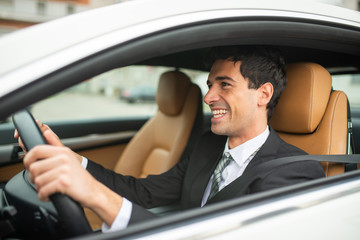 Smiling business man driving his new car