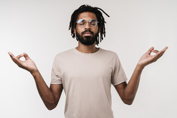 Meditating african guy isolated over grey wall
