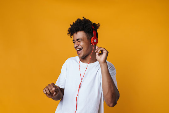 Image of excited african american guy listening music with headphones