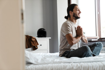 Young man meditating in bedroom