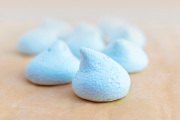 A group of fresh meringues of blue color on backing sheet. Sweet fluffy candies, cooking creamy treat from egg and sugar, homemade creamy treat, dessert, pastry shop, selective focus food background.