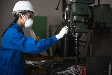 Woman engineering technician working on machinery drilling metal with with job in working carefully handle.