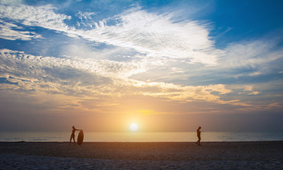 Surfer walking down the beach to the waters edge with surfboard.