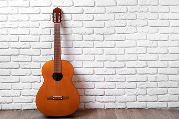 One guitar on the floor against white brick wall