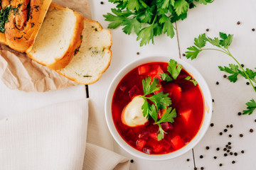 Borscht with fresh bread on a natural wooden background. Red beetroot soup with fresh bread