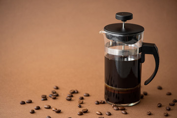 coffee pot with black coffee on brown background