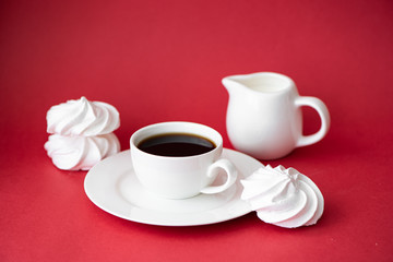cup of black coffee with marshmallows on a red background