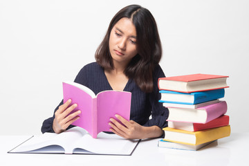 Young Asian woman read a book with books on table.