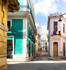 Road in old Havana with green car in front of colorful buildings.