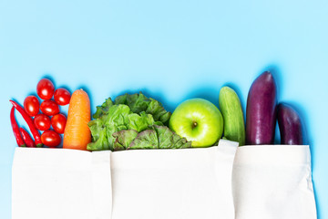 Various vegetables and fruits in a beige eco bag on blue background