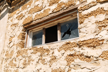 Rough texture of a brick wall made of shells. Broken glass in a building window. Housing problems.