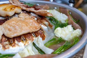 A preparation of roasted meat with sauce of vegetable on Hot Pot - Mu Kratha, close up. Grilled slice pork at Thai Barbecue style.
