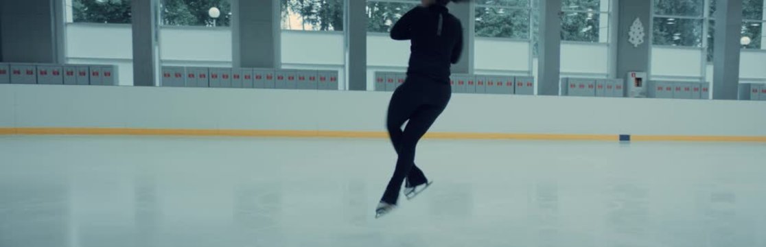 Female ice figure skater falls on ice while practicing jumps on the rink. Shot on RED cinema camera with 2x Anamorphic lens, 75 FPS slow motion