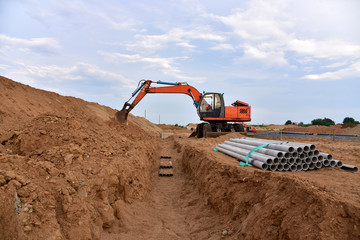 Excavator dig the trenches at a construction site. Trench for laying external sewer pipes. Sewage...