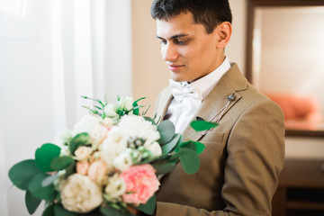 Beautiful man, groom holding big and beautiful wedding bouquet with flowers