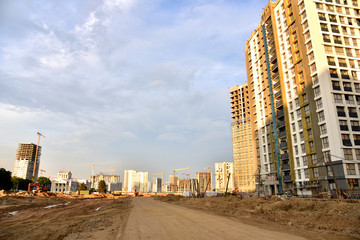 Tower cranes in action at construction site. Construction process of the new modern residential buildings. Road work and streets repair in city. Preparing to pour of concrete into formwork. Soft focus