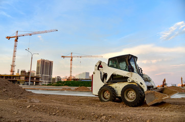 Skid-steer loader working at construction site. Сompact construction equipment for work in limited...