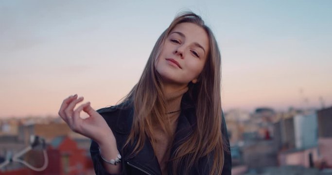 Portrait of a pensive smiling young girl with long hair illuminated by a soft evening sunset light during golden hour. Slow Motion