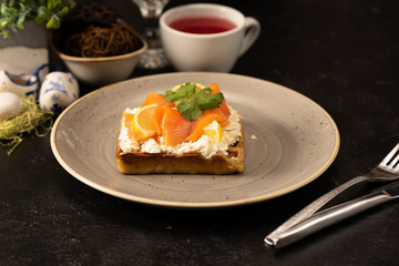 Belgian waffles with cottage cheese, cream cheese and pickled salmon with lemon, garnished with parsley leaves for breakfast. A healthy dessert for tea or coffee.