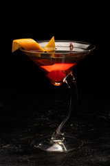 Alcoholic cocktail in a transparent glass goblet on a black background.