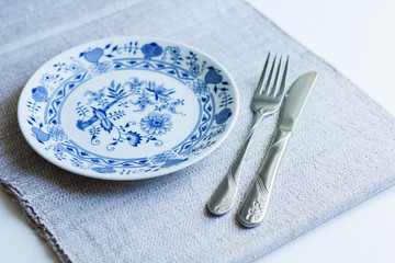 Table setting for dinner: a plate, a fork, a knife on a woven cloth napkin with an embroidered...