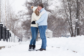 Fototapeta na wymiar Young couple in knitted sweaters hugging in a winter park