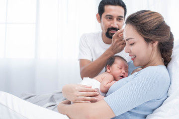 smiling mother and father holding their newborn baby at home..portrait of happy family at home, young parents holding on hands little sweet newborn baby, love and happiness concept.