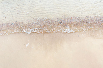 Top view Soft wave of the sea on the sandy beach with white clean foam.
