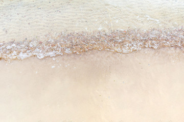 Top view Soft wave of the sea on the sandy beach with white clean foam.