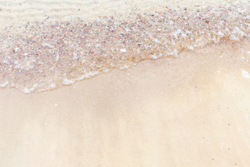 Top view Soft wave of the sea on the sandy beach with white clean foam.
