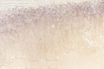 Fototapeta na wymiar Top view Soft wave of the sea on the sandy beach with white clean foam.